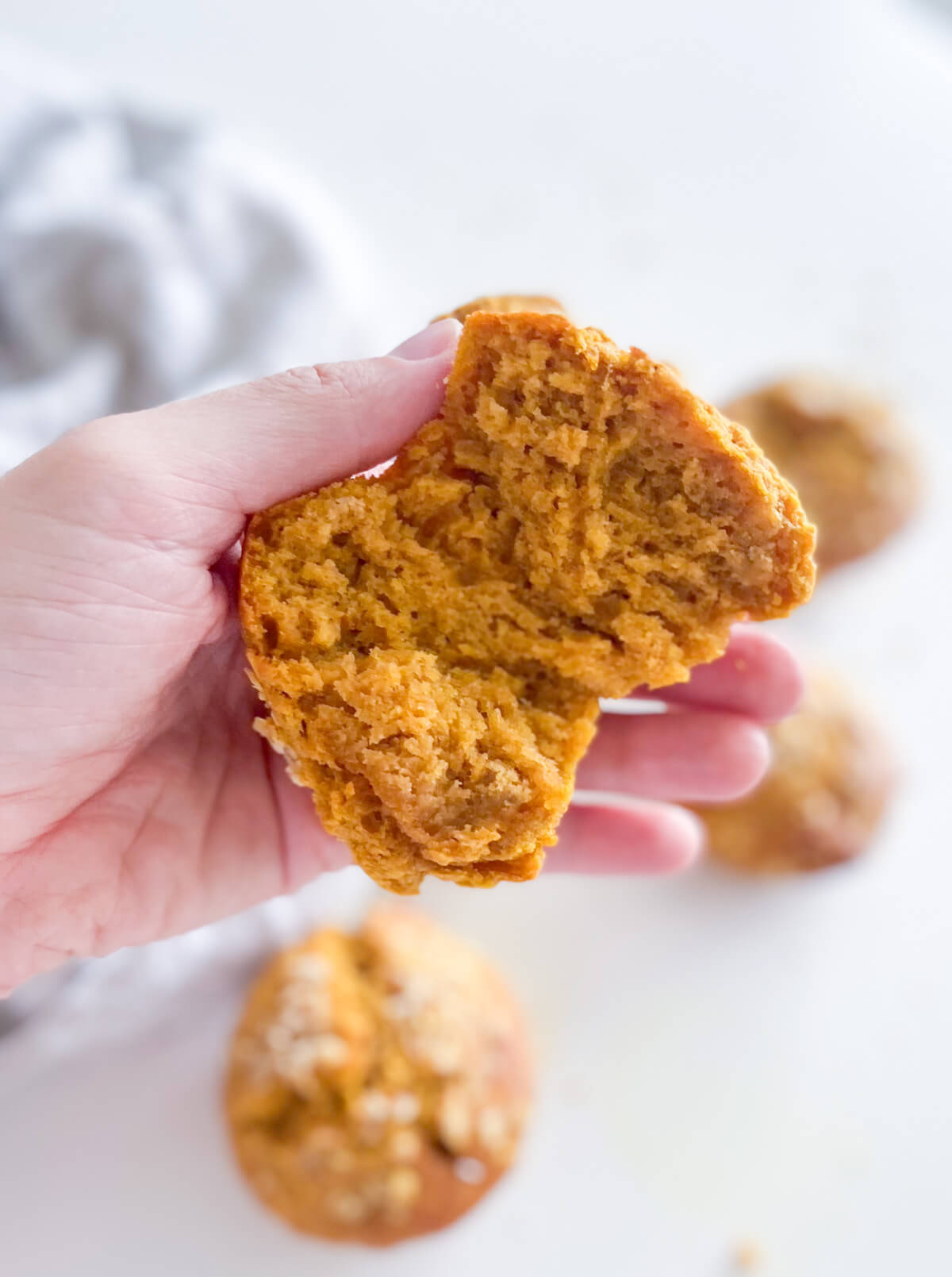 Hand holding a halved muffin to show how moist it is.