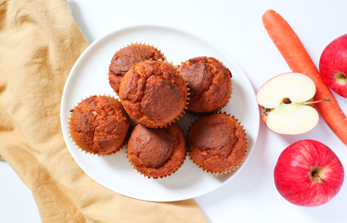 Landscape image of muffins on a plate with fruit and vegetables on the side. 