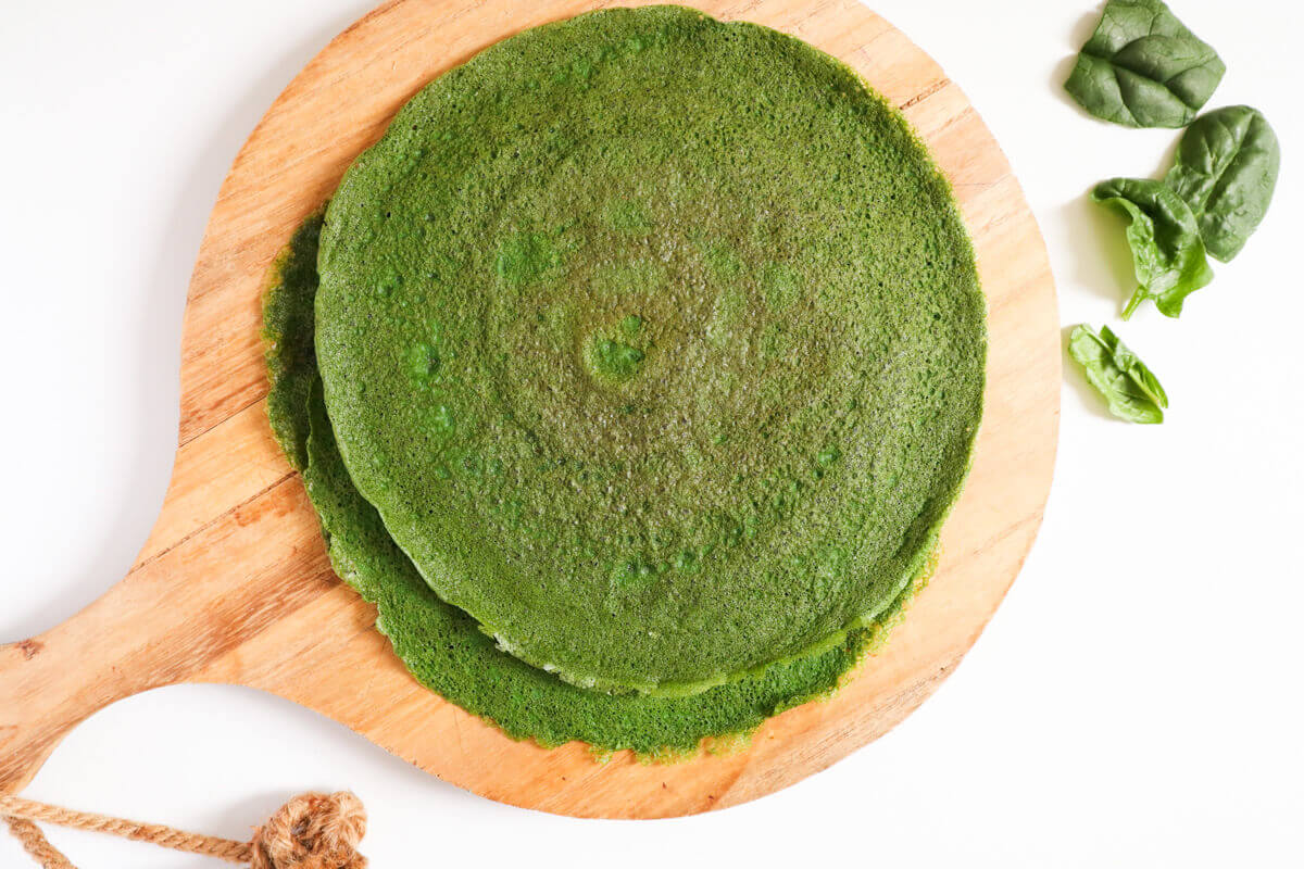 Landscape image of spinach wraps on a wooden board.