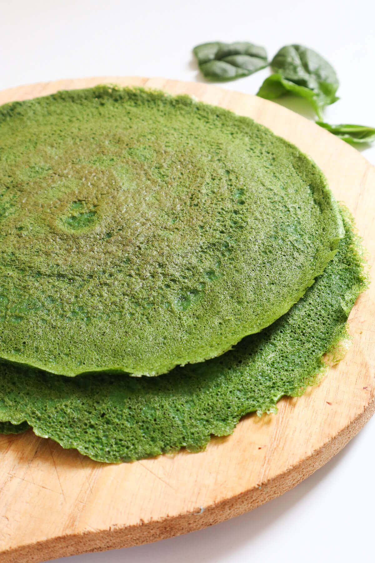 Stack of spinach wraps on a wooden board.