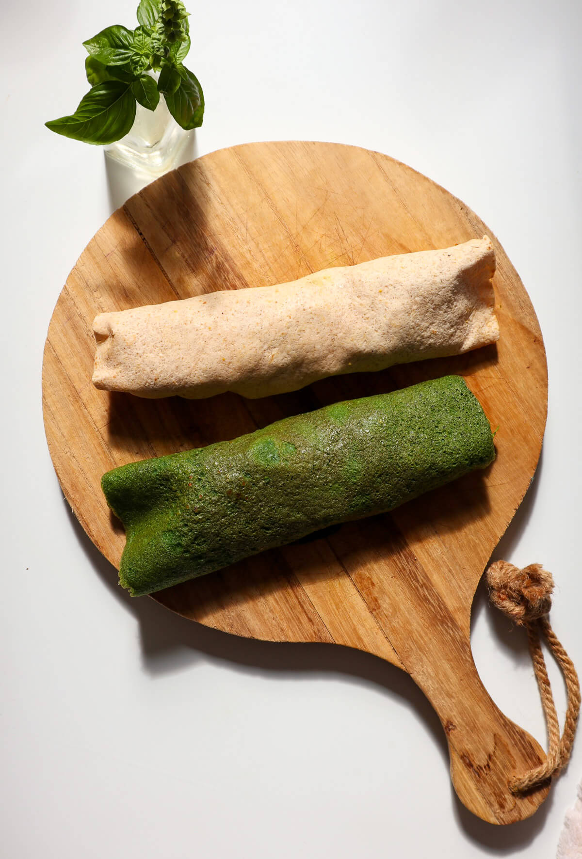 Rolled up flour wrap next to rolled up spinach wrap.