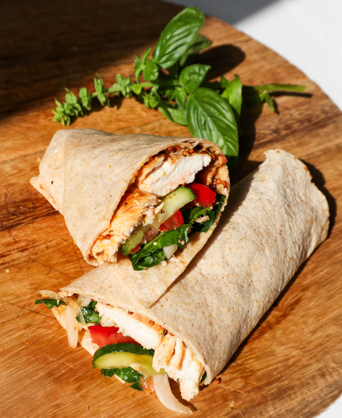 Two wrap half in flour tortilla on a wooden board.