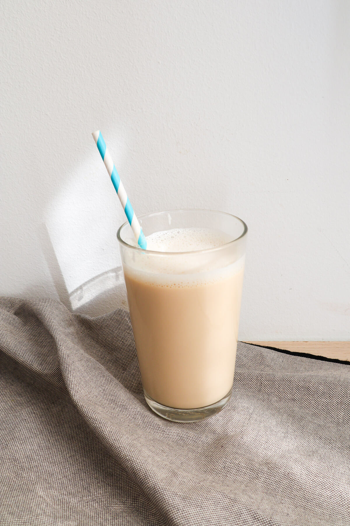 Vanilla milk in a glass with blue straw. 