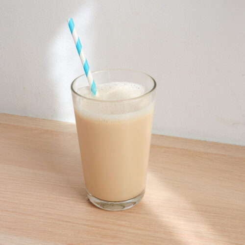 Vanilla milk in a glass with blue straw.