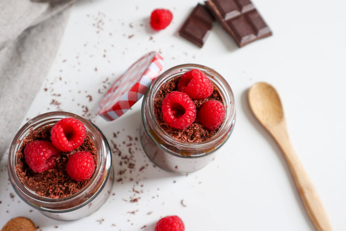 2 chocolate mousses topped with raspberries and chocolate on the side