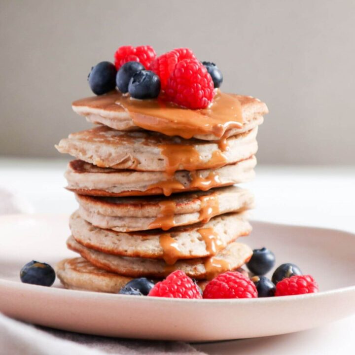 Fluffy Banana Buckwheat Pancakes stacked and topped with fresh fruit and peanut butter.