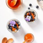 Top down chia puddings with honey and decorations on the side.