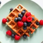 Gluten-free banana buckwheat waffles topped with berries.