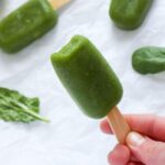 Hand holding a green popsicle.