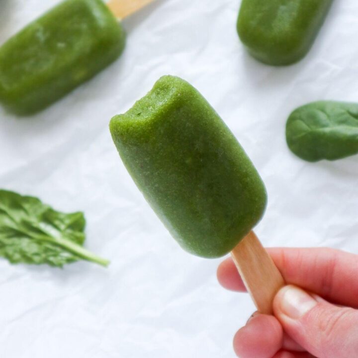 Hand holding a green popsicle.