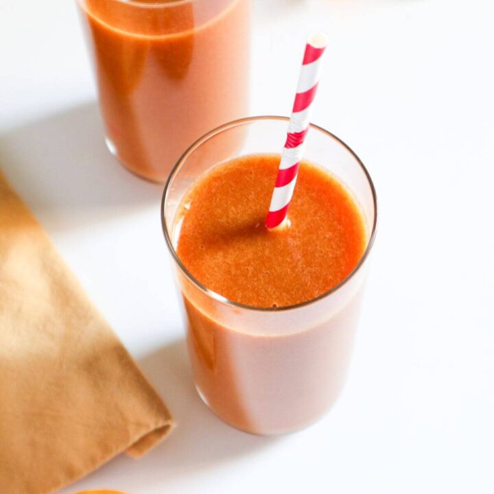 Peach juice in a glass with a straw