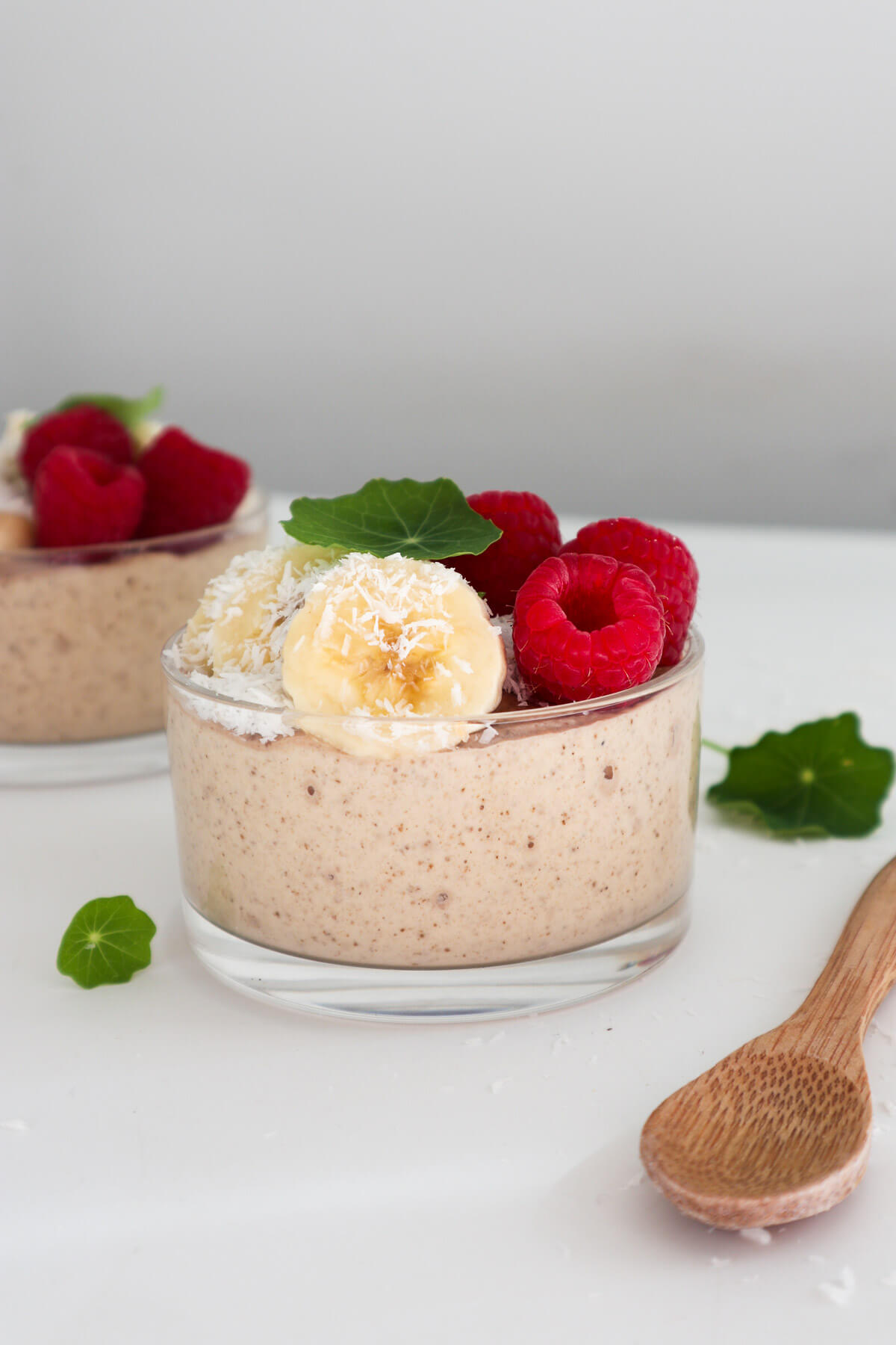 Blended vegan banana pudding eye level view in a cup topped with berries and banana.