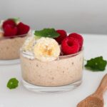 Vegan banana pudding topped with banana, berries and coconut flakes.